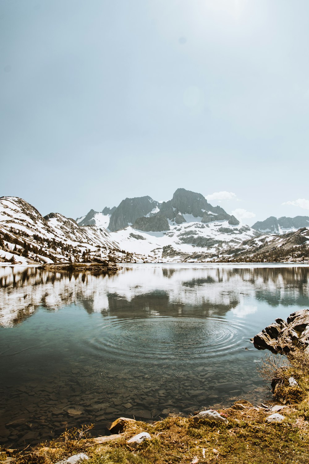 specchio d'acqua circondato da montagne coperte di neve durante il giorno