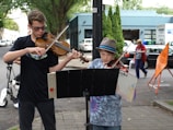 A duo of violinists playing under colorful street lights at dusk.