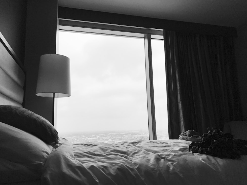 grayscale photo of bed near white table lamp