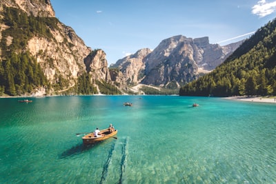 three brown wooden boat on blue lake water taken at daytime landscape google meet background