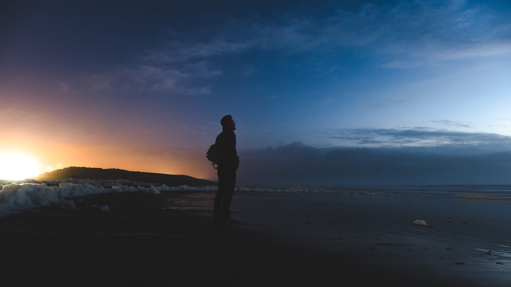 man standing on seashore facing sea