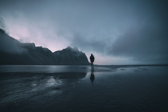 man standing on seashore during daytime in Stokksnes Iceland