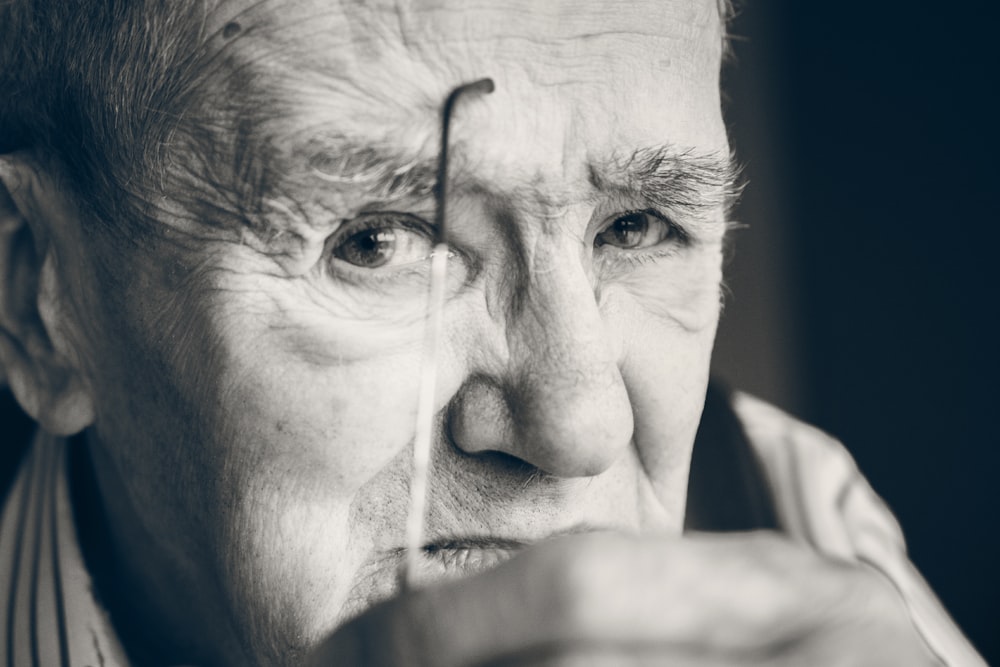 grayscale photo of a man holding eyeglasses