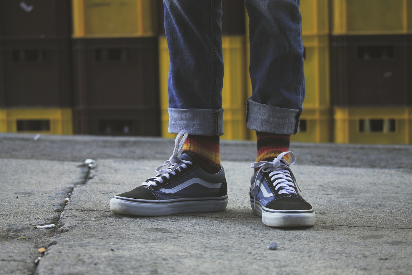 Person wearing black and white Vans Old Skool sneakers on a sidewalk