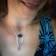 Close-up of a woman wearing a delicate silver necklace with a small gemstone pendant.