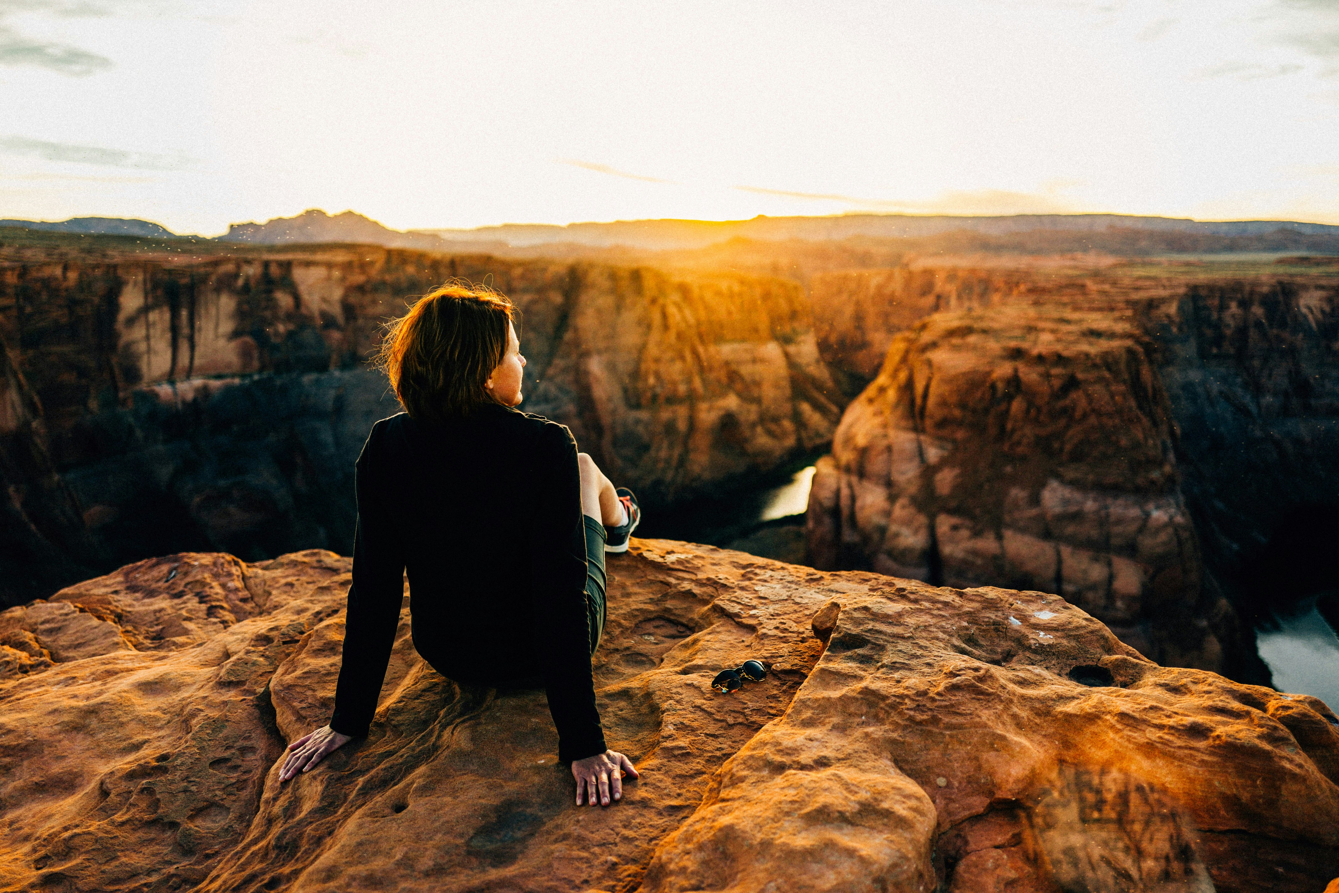 woman sitting on top of cliff