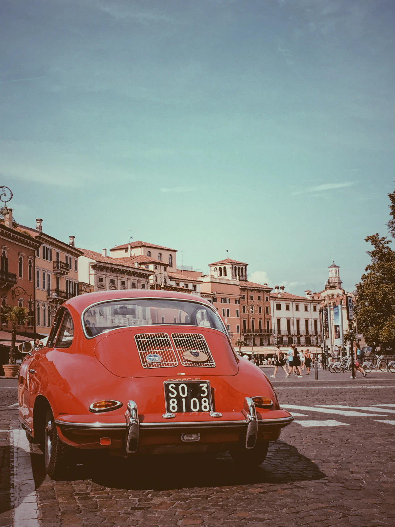 A classic car parked on a cobbled square