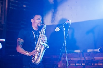 A musician passionately playing a saxophone on stage, surrounded by soft lighting.