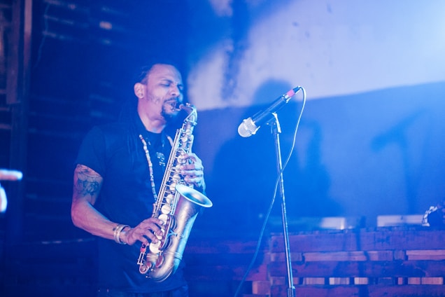 A musician passionately playing a saxophone on stage, surrounded by soft lighting.