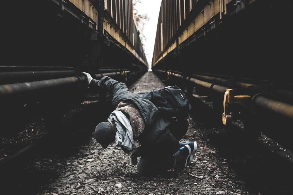 man seating on ground in-between of two brown metal walls