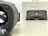 A Daydream View VR headset is positioned prominently on the left, with its gray fabric texture visible. In the background, there is a box featuring an image of the same headset and the Google logo. The setting is minimalist with a light-colored, smooth surface.
