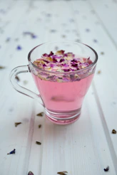 clear glass cup surrounded by petals