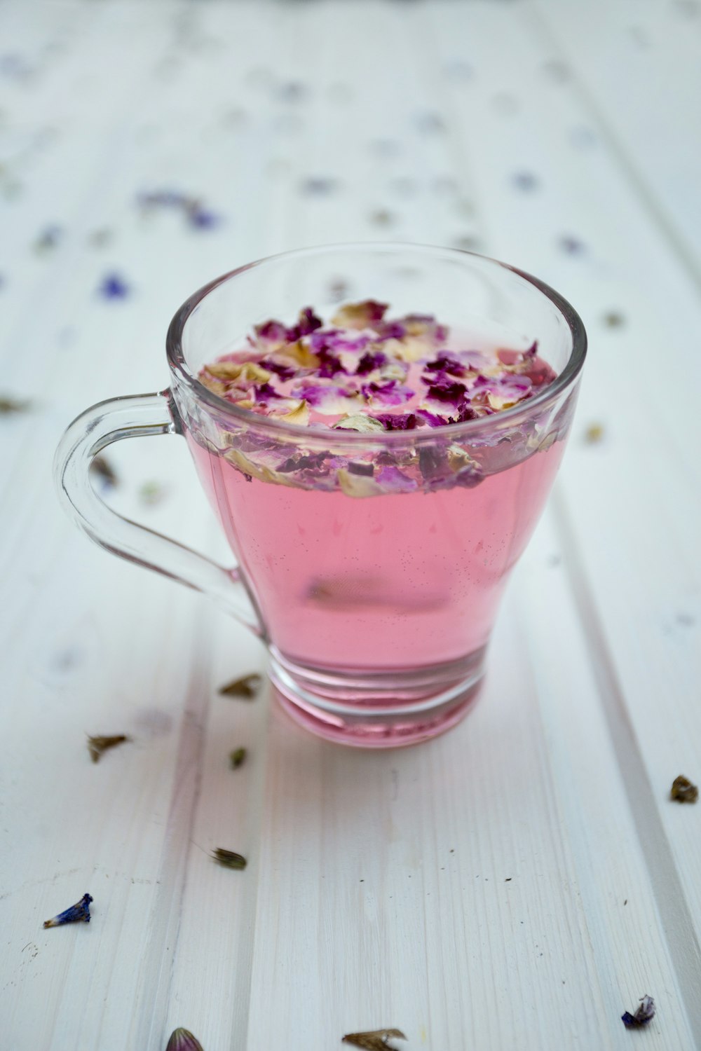 tasse en verre transparent entourée de pétales