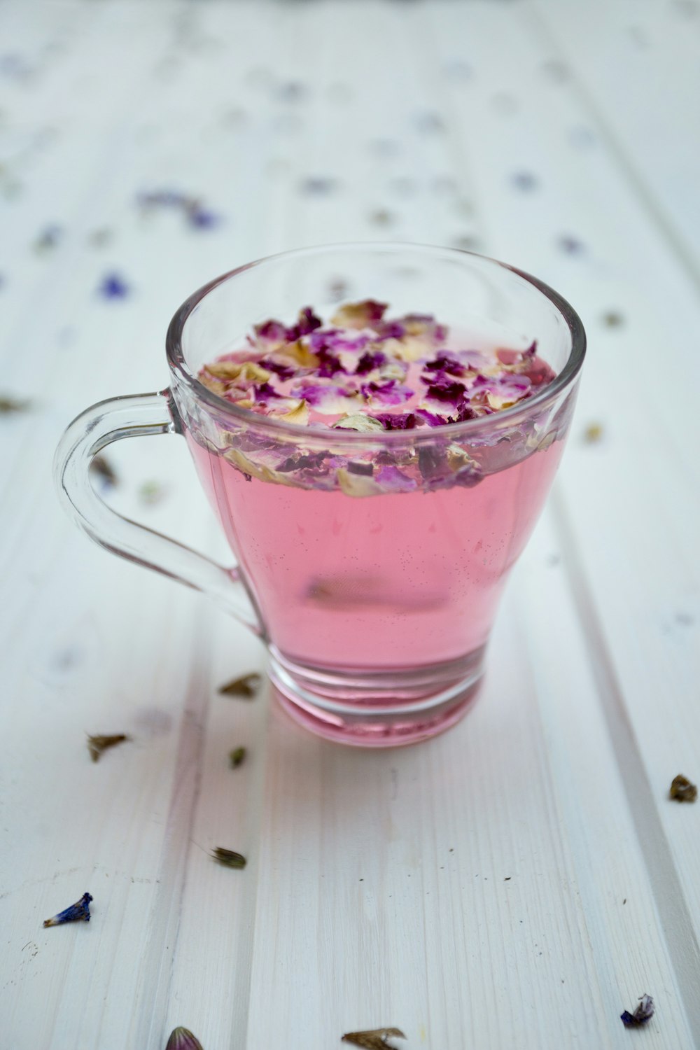 clear glass cup surrounded by petals