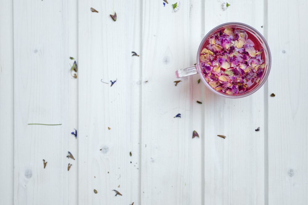 Taza de vidrio transparente con cereal sobre superficie blanca