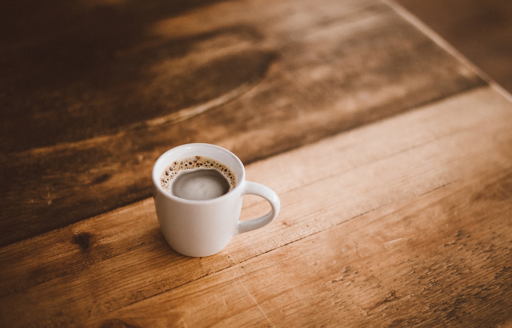 white ceramic mug with coffee on brown wooden table