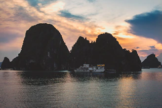 A scenic boat cruising past lush green islands under a golden sunset.