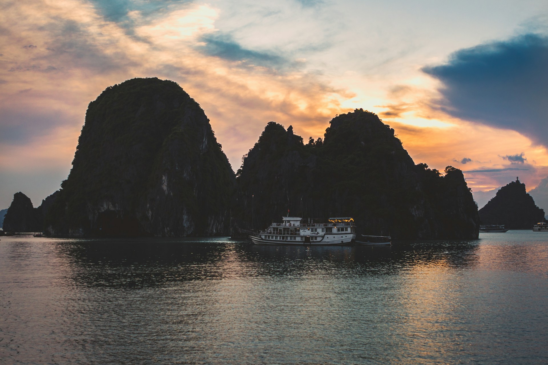 A vibrant sunset over the limestone cliffs of El Nido, with boats gently floating on crystal-clear waters.