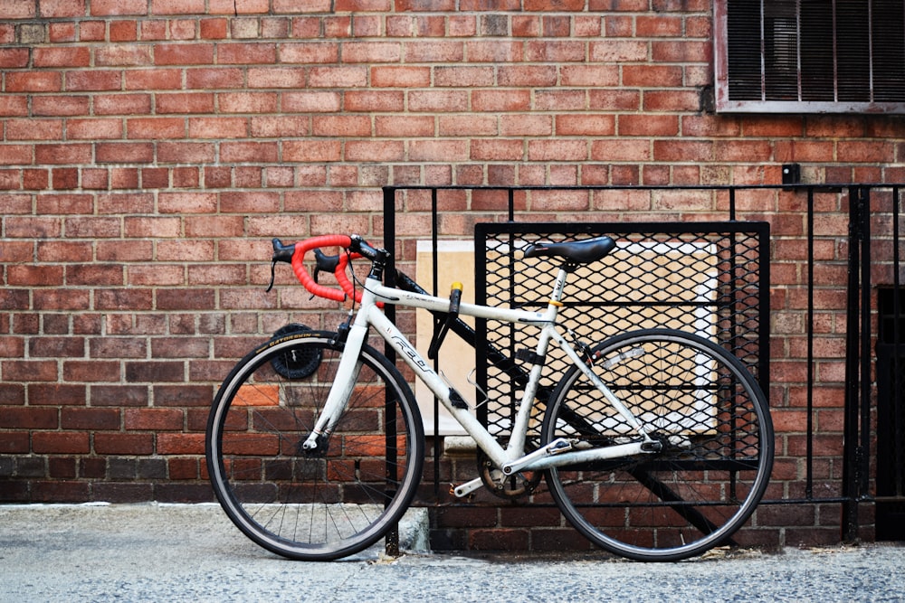 white and black road bike leaning on brown brick wall