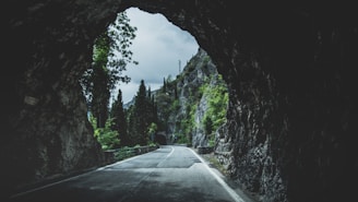 gray concrete road across black cave