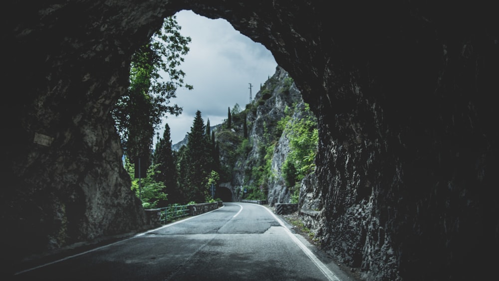 gray concrete road across black cave