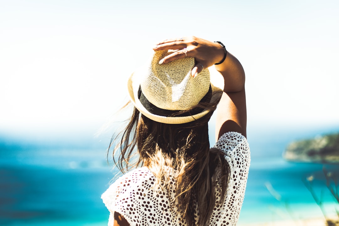 woman holding on to her hat, Woman looking toward ocean