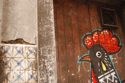 Dynamic close-up of a colorful Screaming Chicken 2.0 logo painted on a textured wall.