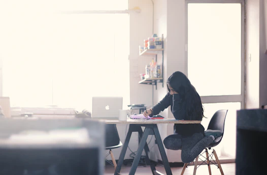 A focused UK student writing an essay at a cozy desk with a laptop and notes, bathed in soft natural light.