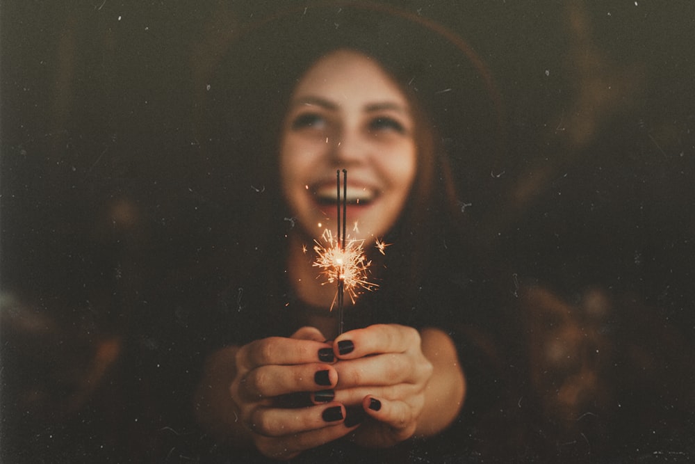woman holding sparklers while smiling