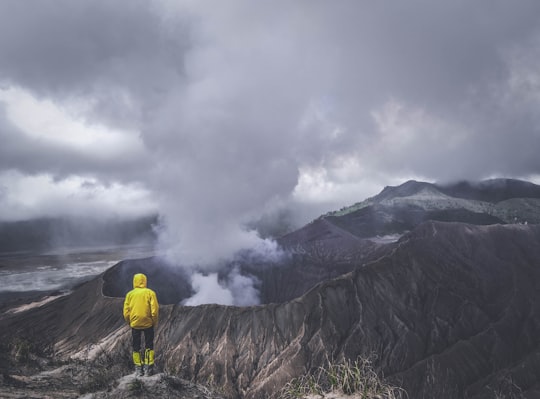 person wearing yellow jacket standing on cliff in Bromo Tengger Semeru National Park Indonesia