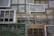 A collection of variously sized and styled window frames arranged in a mosaic-like pattern. The frames vary in color from green to white and brown, displaying a mix of vintage and rustic designs. Some have panes of glass, while others appear more weathered.