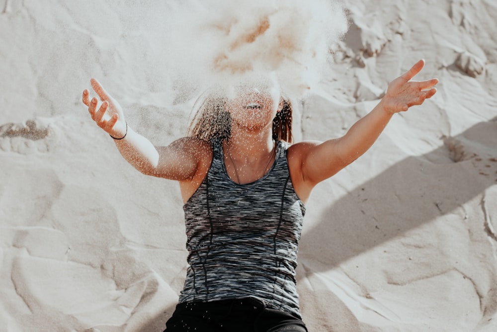 Mujer tirando polvo de arena con los brazos abiertos