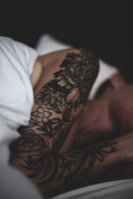 Artistic shot of a cover-up tattoo transforming an old design, framed by soft beige and lilac tones.