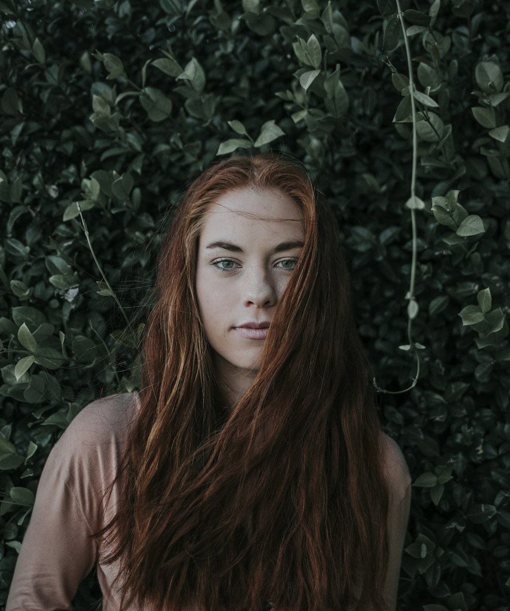 woman leaning on green leaf plant during daytime