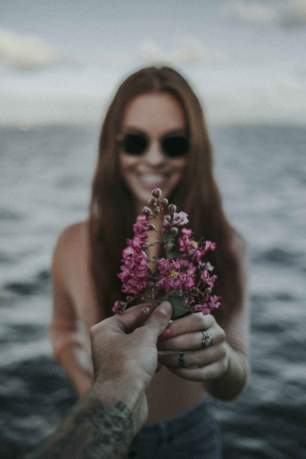 duas mãos segurando flores de pétalas cor-de-rosa