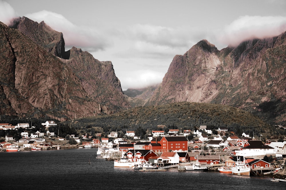 white and brown houses near ocean water and mountains covered with green leafed tress landscape photography