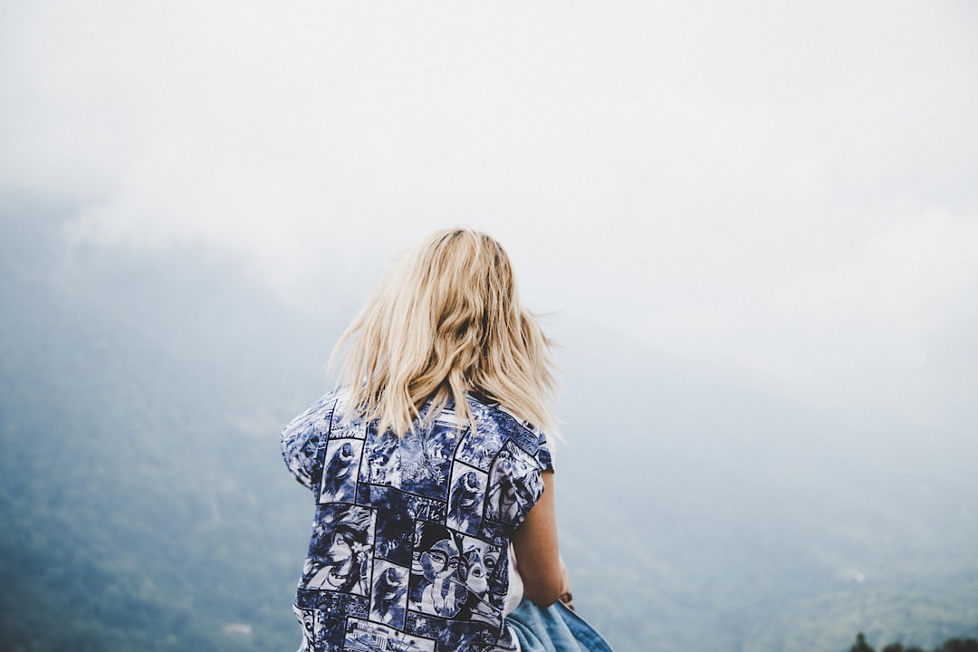 woman facing mountain underneath foggy weather