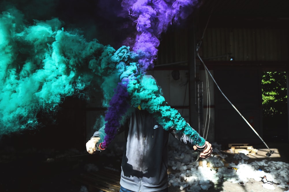 person holding purple and green smoker bottle during daytime