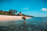 man holding surf board in body of water
