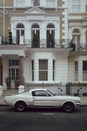 white coupe front of house