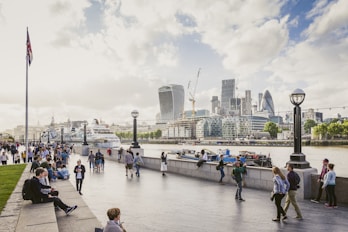 Tourists strolling on the bank of Thames with the City of London visible on the other shore