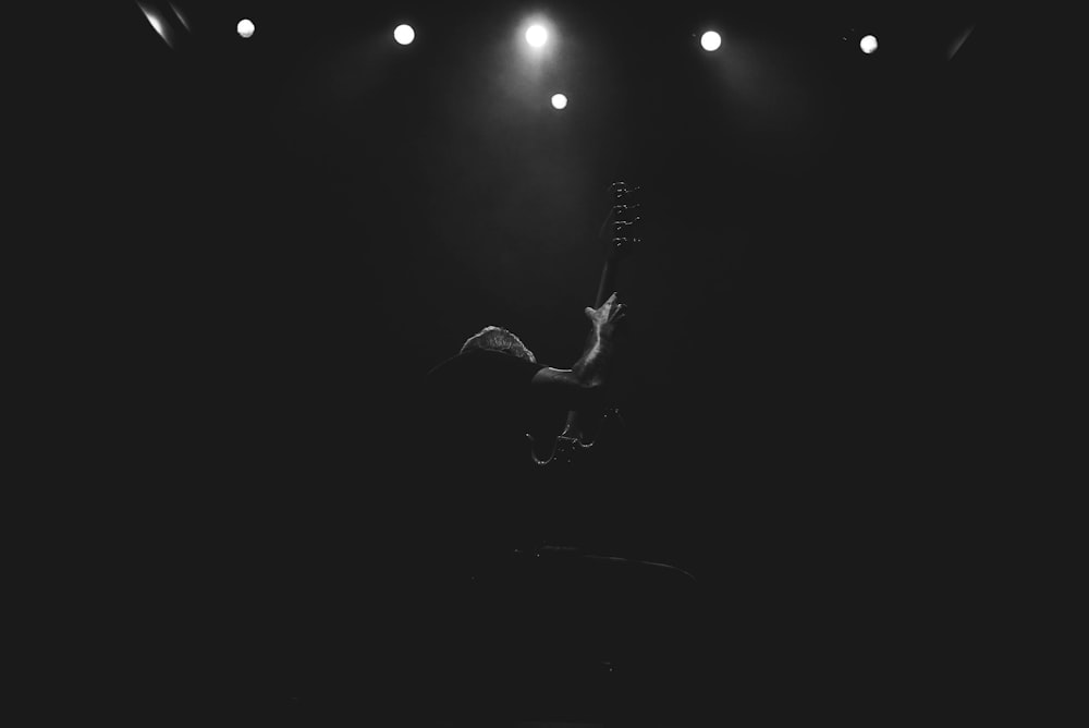 grayscale photo of man playing guitar