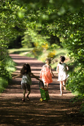 Children playing freely on a sunlit path, their faces glowing with happiness and natural warmth.