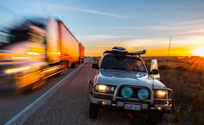 A fast-moving cargo truck on a highway at sunset.