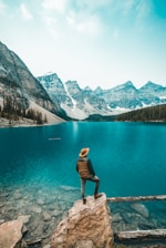 man standing on rock near lake