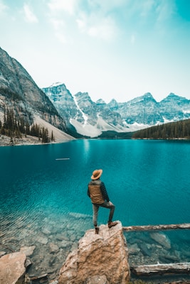 man standing on rock near lake