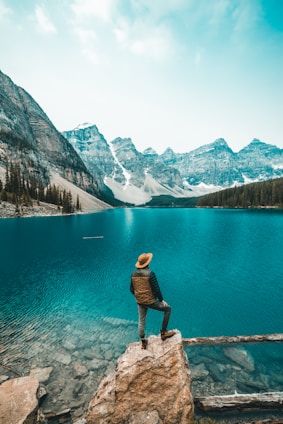 man standing on rock near lake