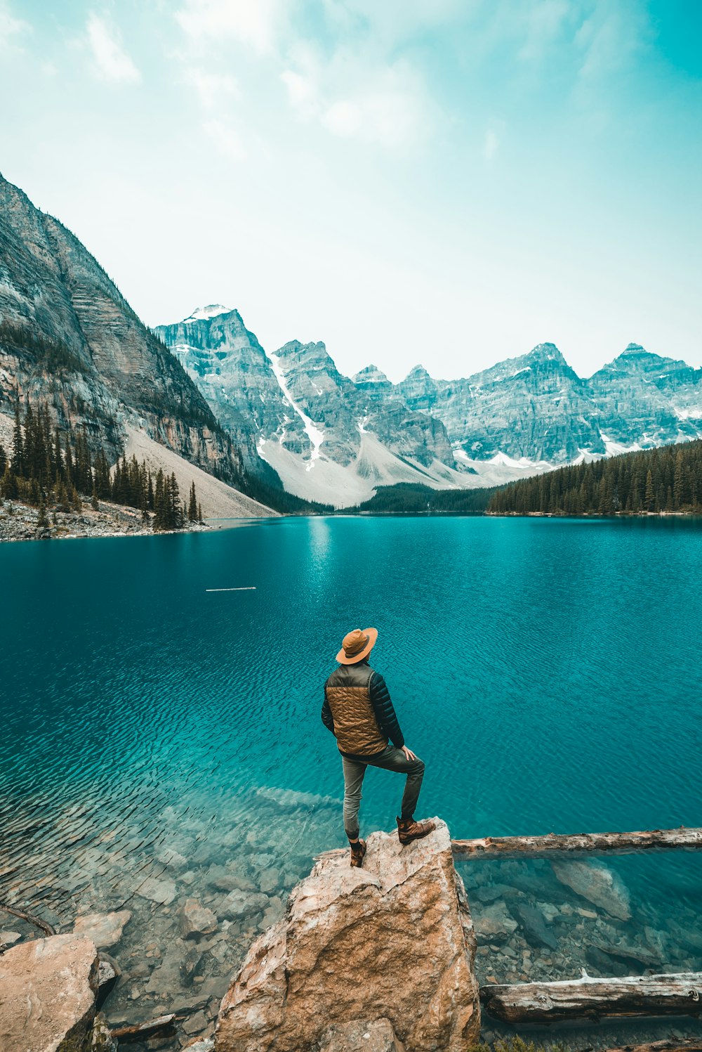 man standing on rock near lake