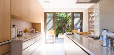 white wooden kitchen island and cupboard cabinets near glass panel door