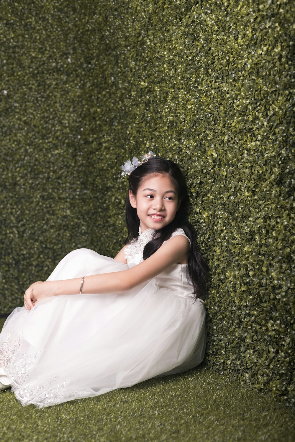 girl sitting and leaning on hedge